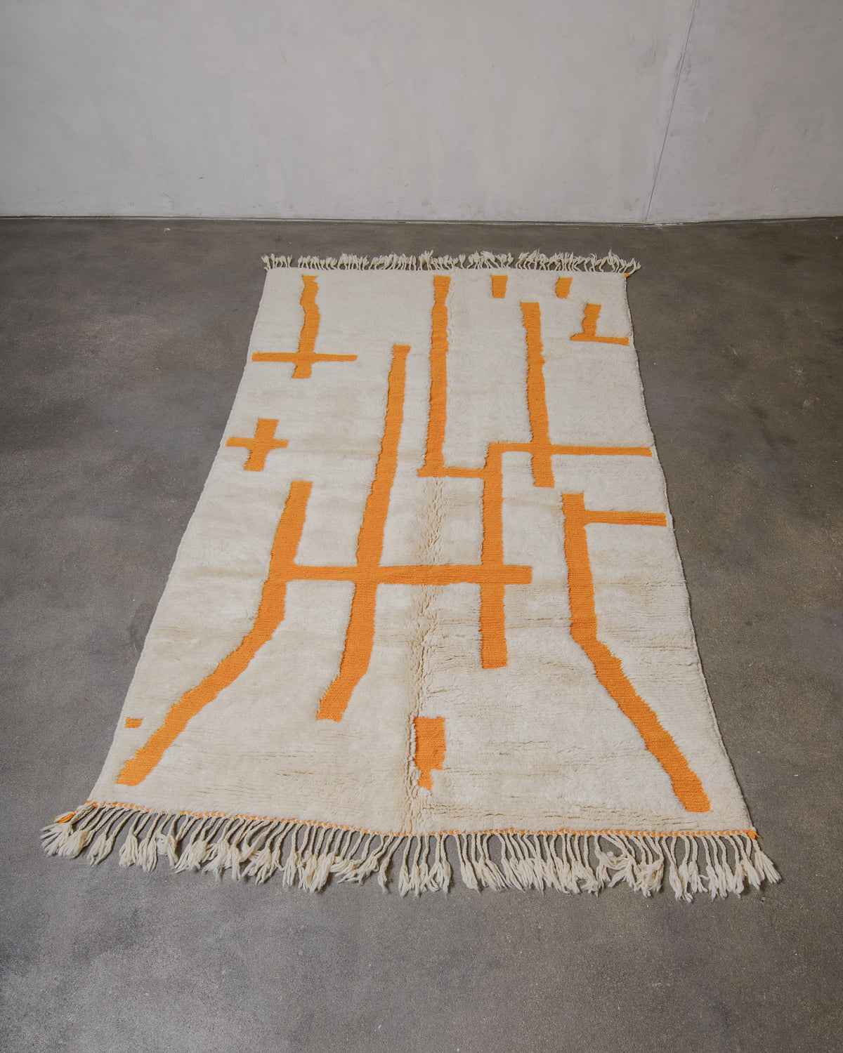 Cream wool rug with saffron yellow geometric patterns on a gray floor.